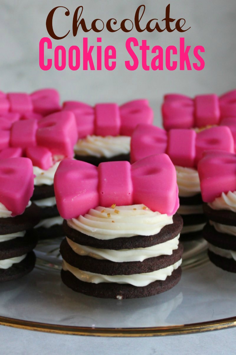 chocolate cookies stacked with layers of piped white frosting in between with pink chocolate bows on top and title text on pic.