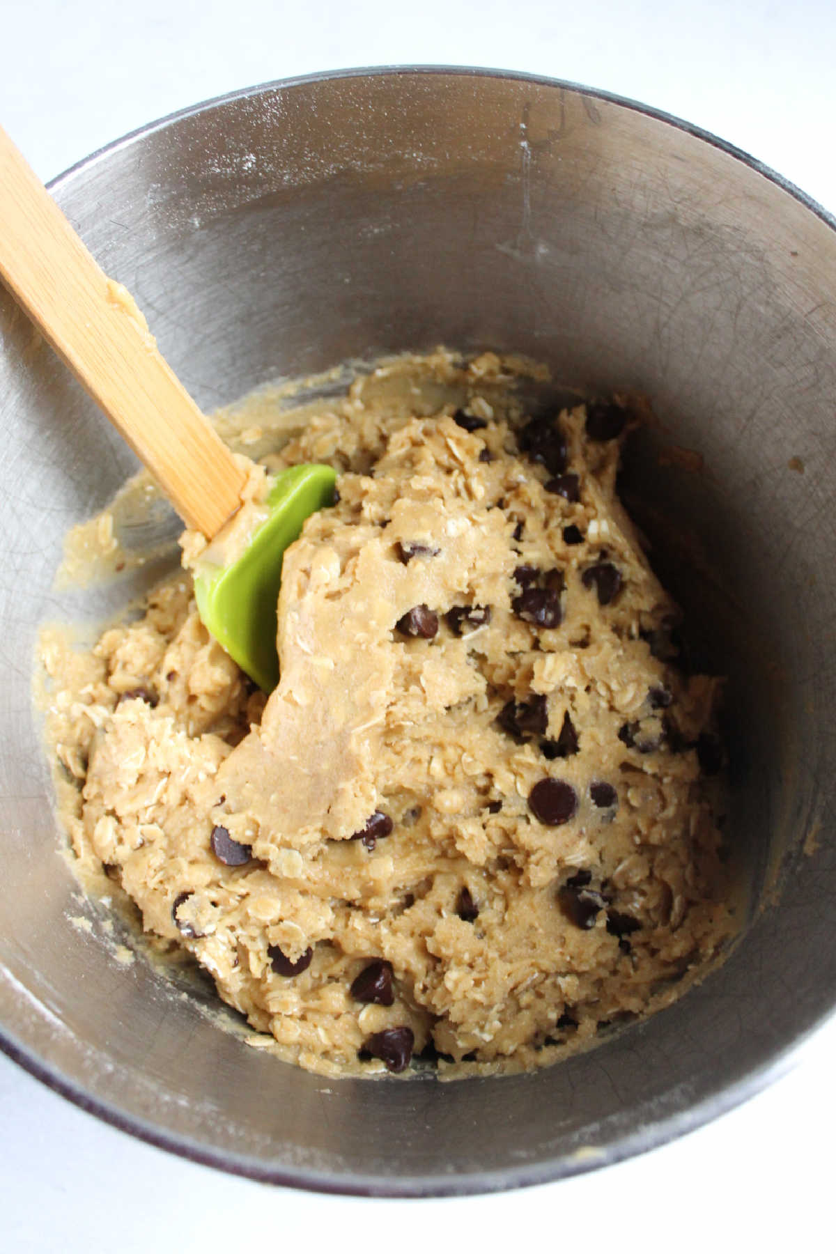 Mixer bowl filled with cowgirl cookie dough with oats and chocolate chips.