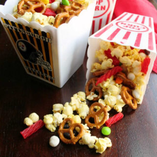 small popcorn tubs full of movie theater snack mix with popcorn and candy.