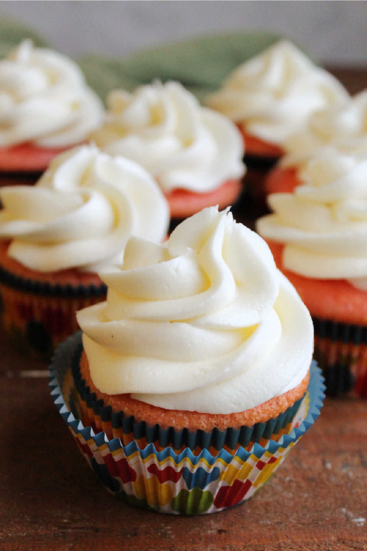 Ruffle swirls of decorator's cream cheese frosting piped on strawberry cupcakes using a star tip.