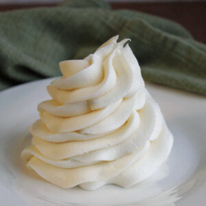 Piped ruffled swirl of decorator's cream cheese frosting on plate showing smooth creamy texture and ability to hold its shape.