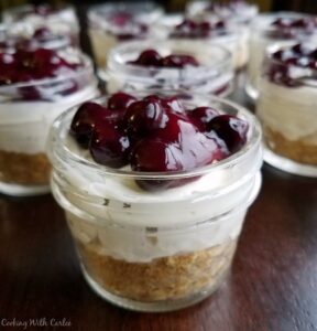 small jars with graham cracker crust, no bake lemon cheesecake filling and blueberry topping