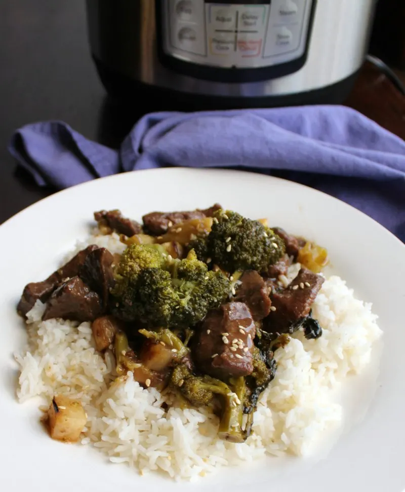 close plate of backstrap and broccoli served on rice with instant pot in background.