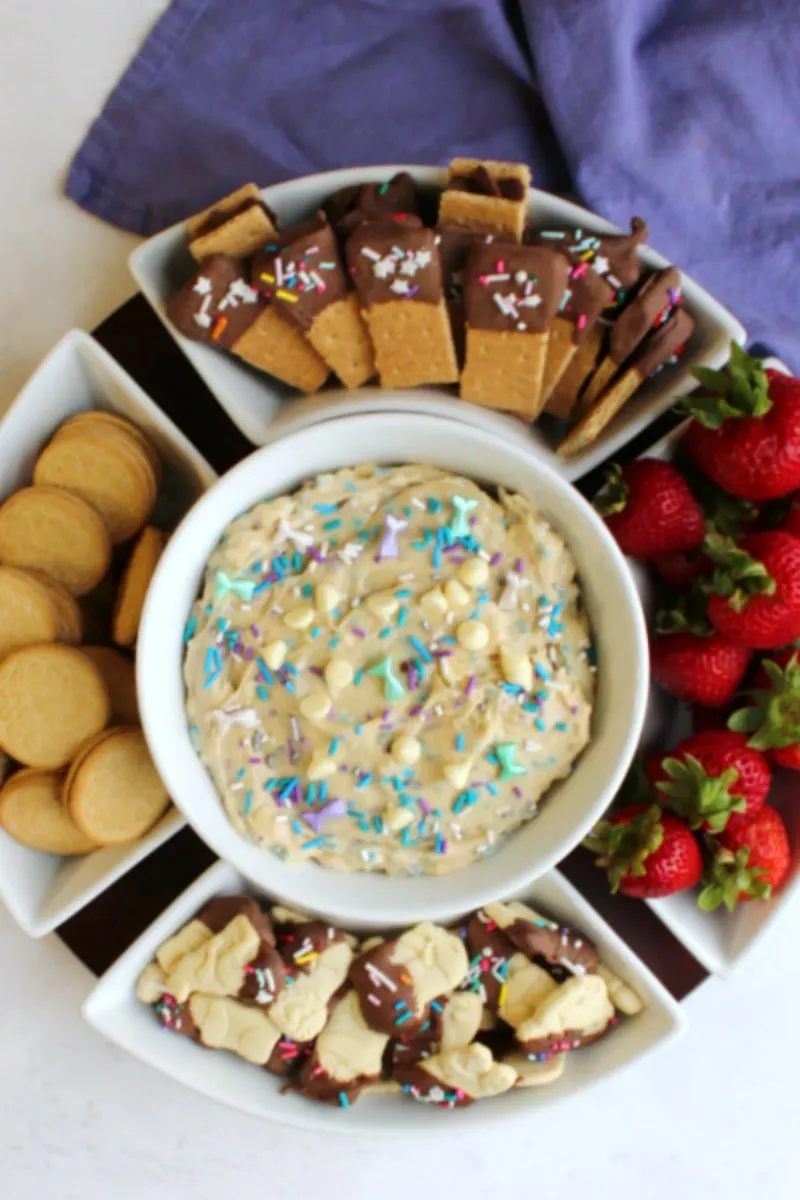 bowl of sprinkle filled birthday cookie dough dip with strawberries, golden oreos, graham crackers and animal crackers for dippers.