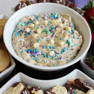 Bowl of cookie dough dip with lots of colorful sprinkles and white chocolate chips.