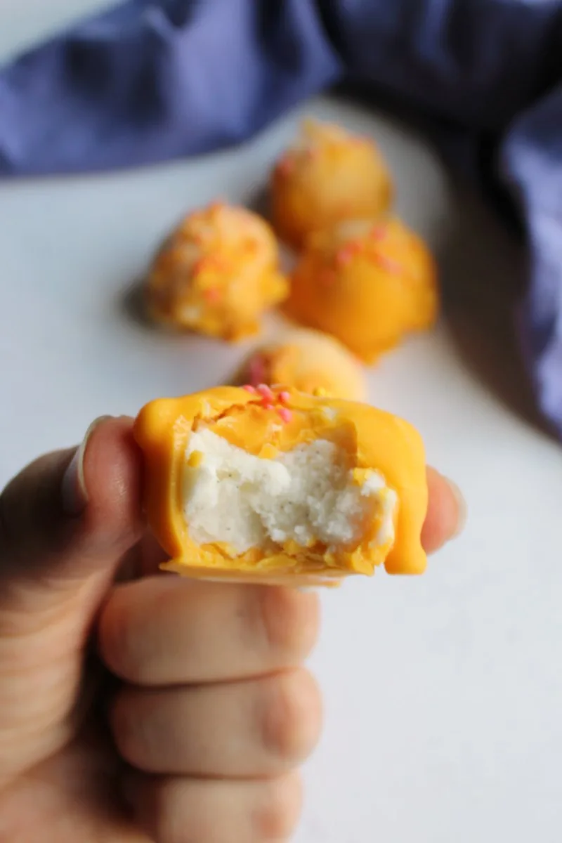 bite out of an orange cream bon bone with vanilla ice cream exposed.