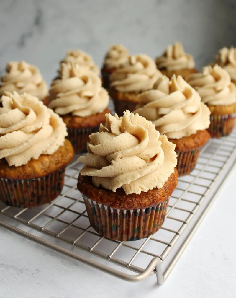 cooling rack full of banana cupcakes with swirls of peanut butter buttercream.