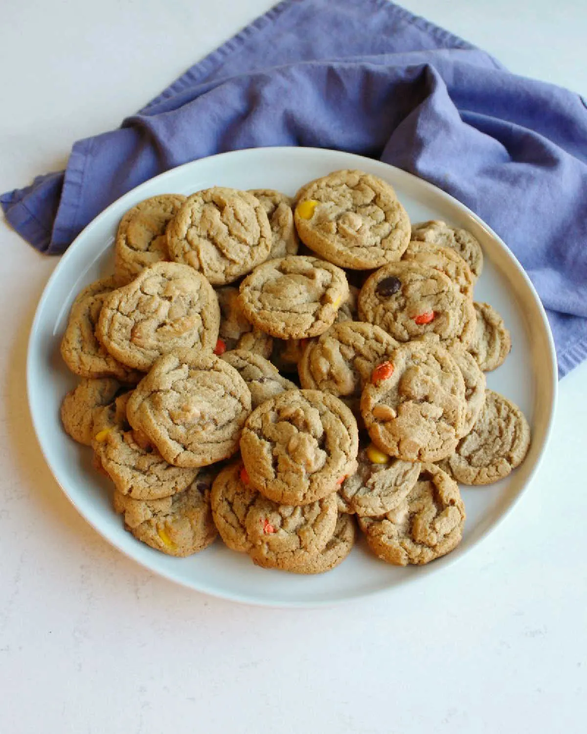 Plate filled with peanut butter cookies with peanut butter chips and candies ready to eat. 