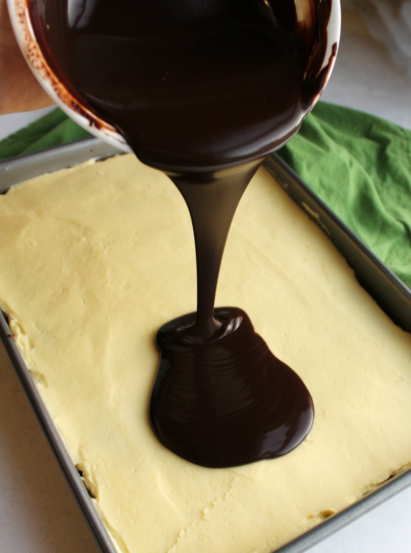 Pouring warm ganache over german buttercream topped cake.