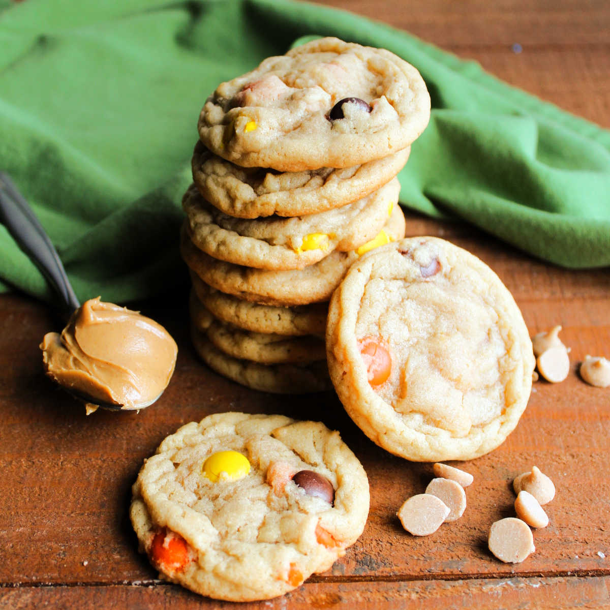 Stack of chewy triple peanut butter cookies with extra peanut butter chips and a spoonful of creamy peanut butter nearby.