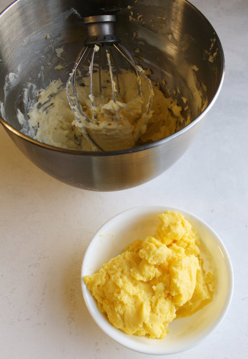 Whipped butter in mixer bowl next to bowl of thick dough like chilled custard, ready to be incorporated into buttercream.