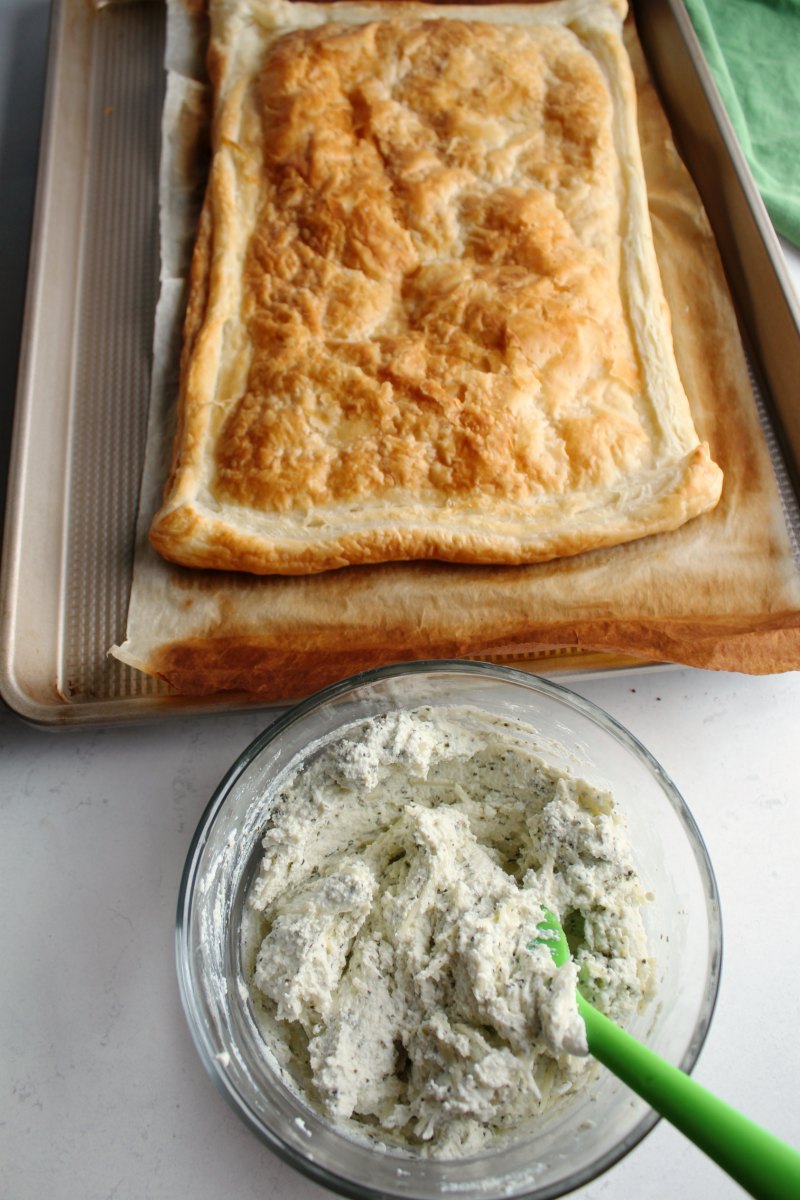 prebaked puff pastry sheet next to bowl of herbed ricotta ready to put together tomato tart.
