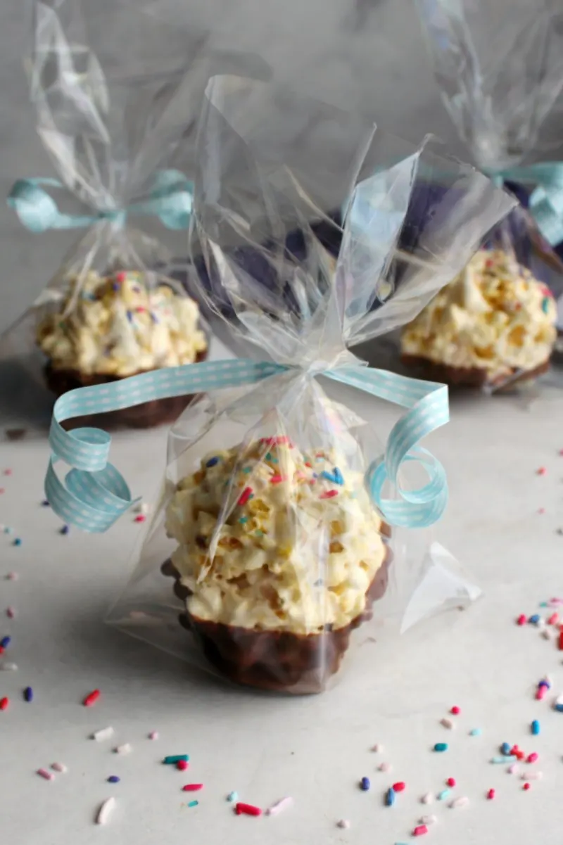 cellophane wrapped chocolate dipped marshmallow popcorn balls with sprinkles and curling ribbon.