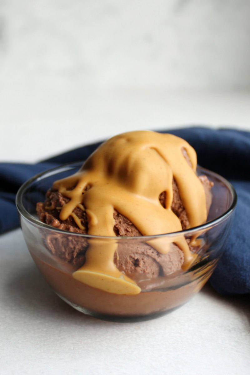 bowl of chocolate peanut butter banana ice cream with peanut butter magic shell on top with blue napkin.