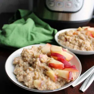 two bowls of creamy maple cinnamon steel cut oatmeal with fresh peaches on top in front of instant pot.