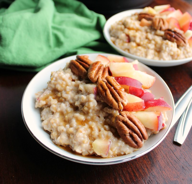close up of bowl of maple cinnamon steel cut oats with pecans and fresh peaches on top.
