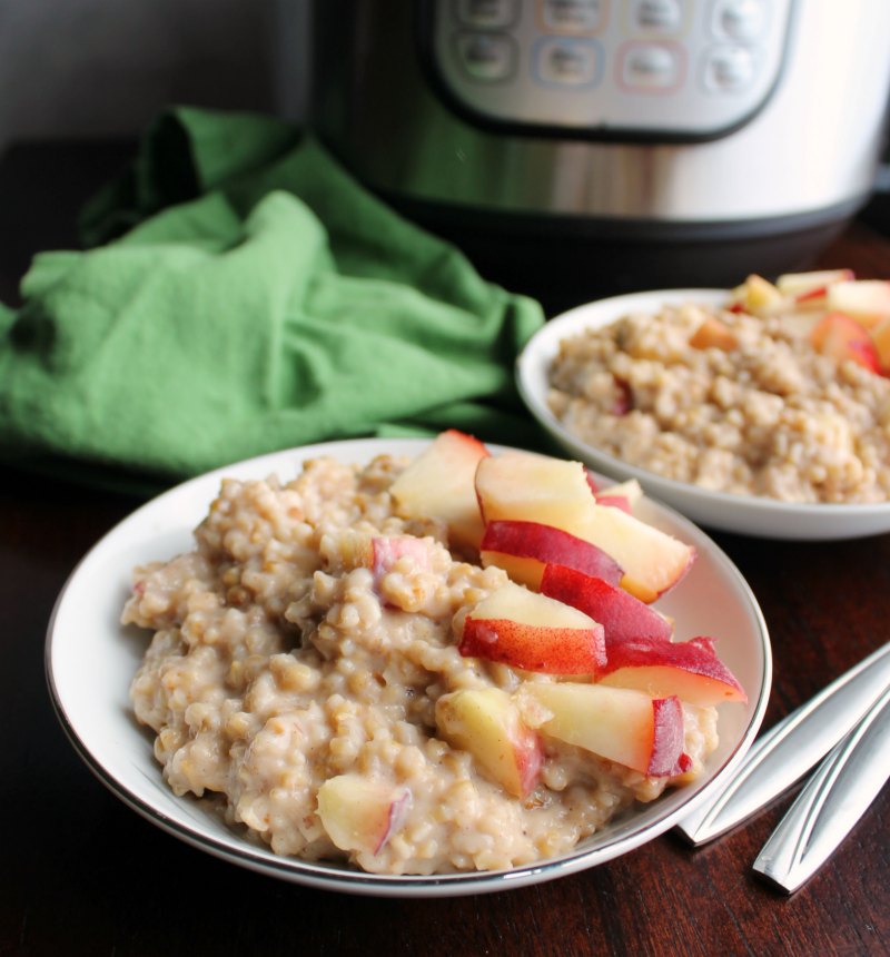 two bowls of creamy maple cinnamon steel cut oatmeal with fresh peaches on top in front of instant pot