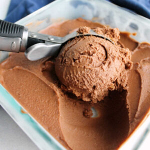 ice cream scoop dipping out first ball of chocolate peanut butter nice cream, showing creamy texture and deep chocolate brown color.