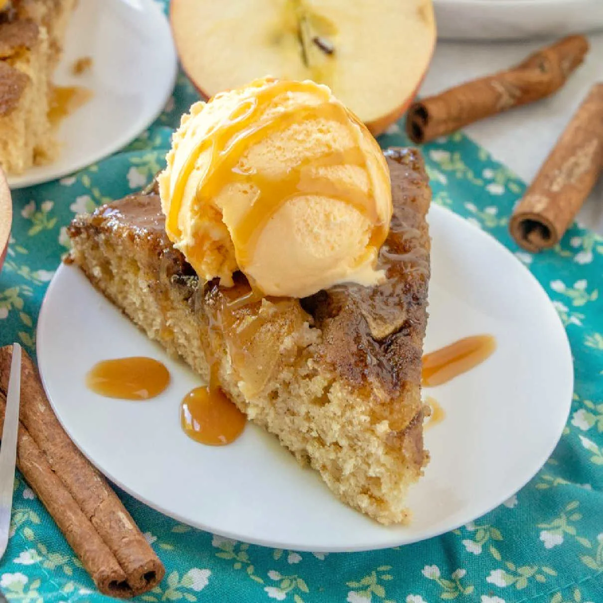 close slice of warm upside down caramel apple skillet cake with scoop of ice cream and drizzle of caramel sauce.