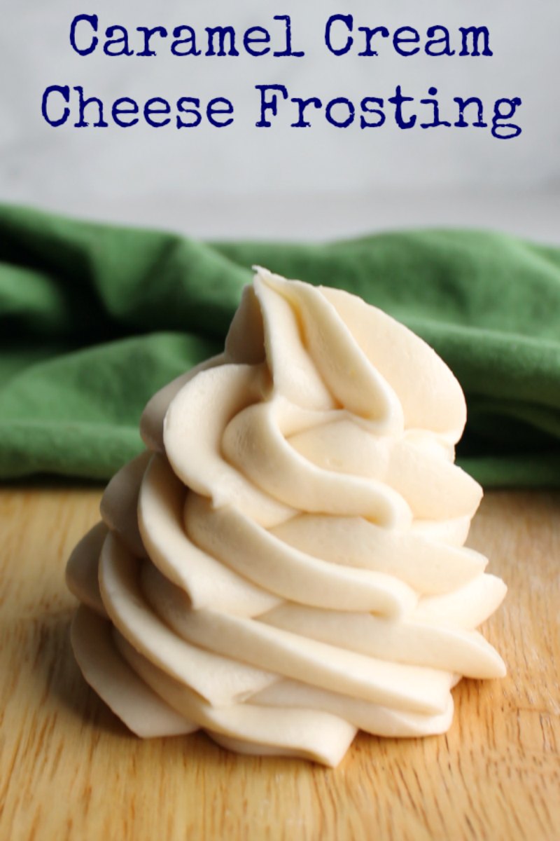 swirl of caramel cream cheese frosting on wood cutting board.