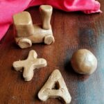 chocolate peanut butter dough shaped into letters, a sphere and a train.