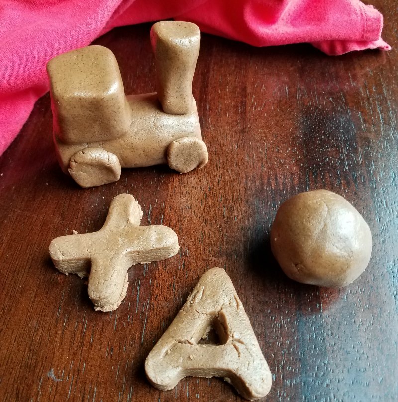 chocolate peanut butter dough shaped into letters, a sphere and a train.