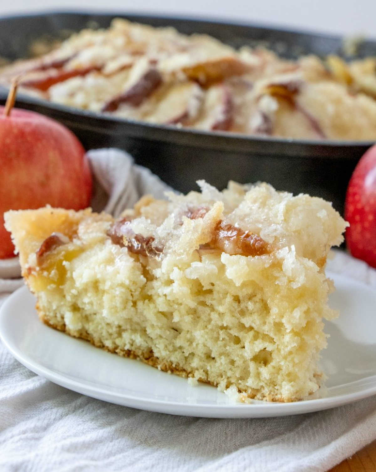 looking across a slice of old fashioned dutch apple cake showing shortcake like cake texture and golden buttery streusel on top.
