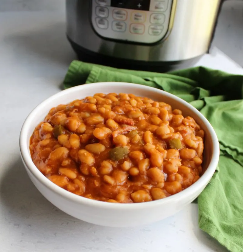 looking across a bowl of homemade maple baked beans with pressure cooker in background.