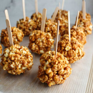 Caramel apple popcorn balls with popsicle sticks to look like caramel apples.