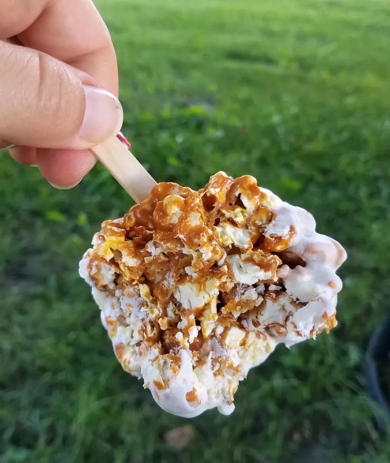 white chocolate dipped caramel apple popcorn balls with bites missing.