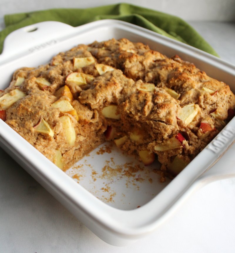 square pan of rustic buttermilk apple cake with corner piece missing.