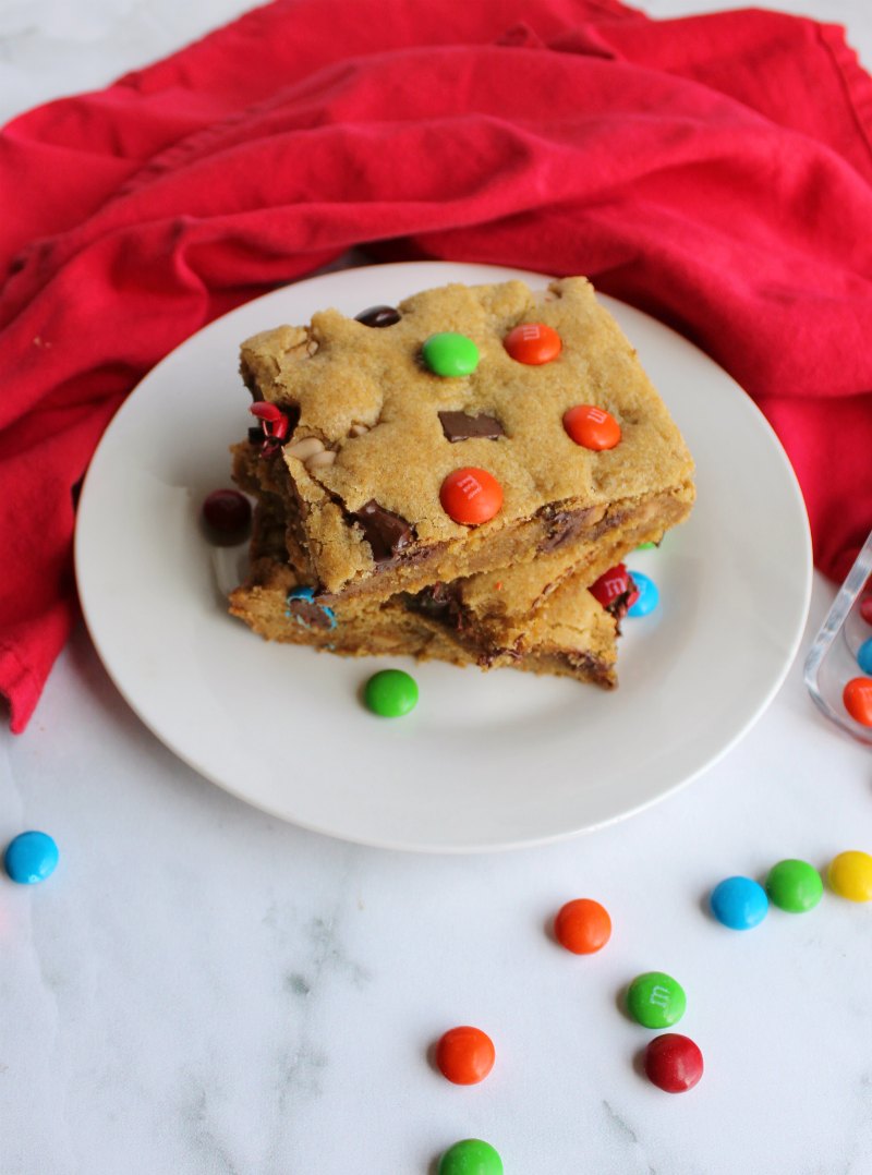 looking down on a couple of pieces of chewy salted caramel m&m blondies on plate with candies scattered around.