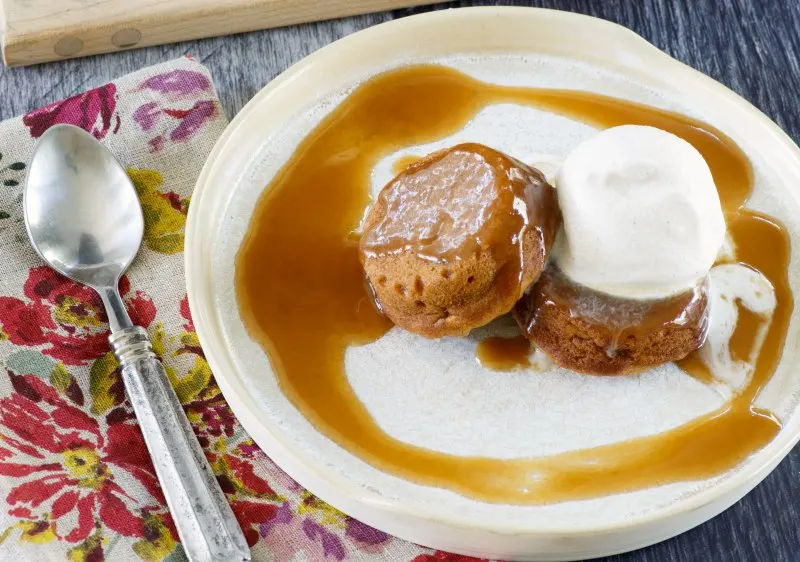 plate with two mini sweet potato cakes, a scoop of ice cream and sticky caramel sauce ready to eat.