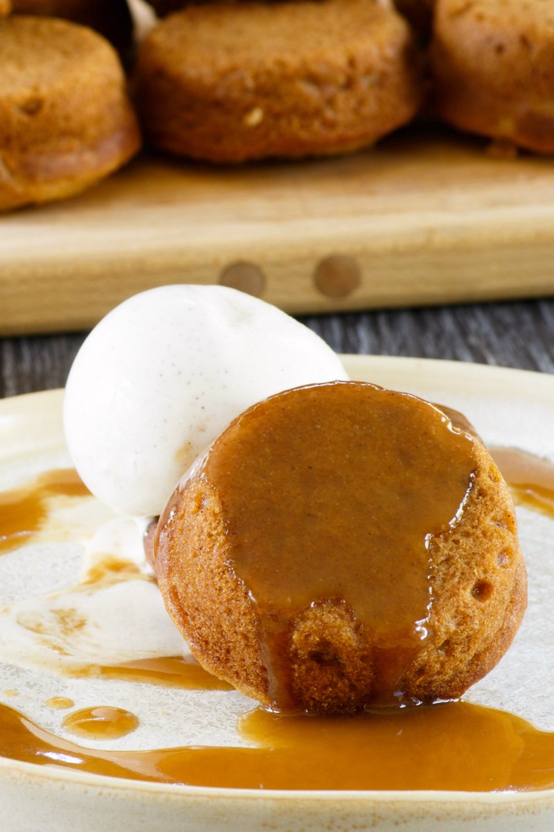 Small cupcake sized sweet potato cake with scoop of ice cream and caramel sauce.