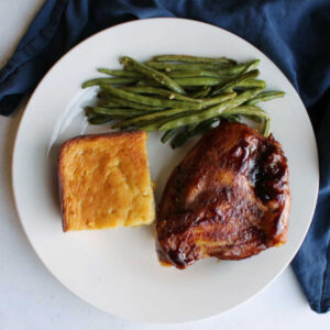dinner plate with oven baked bbq chicken breast roasted green beans and corn casserole.
