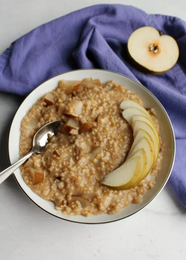 bowl of honey pear steel cut oats with pear halves nearby