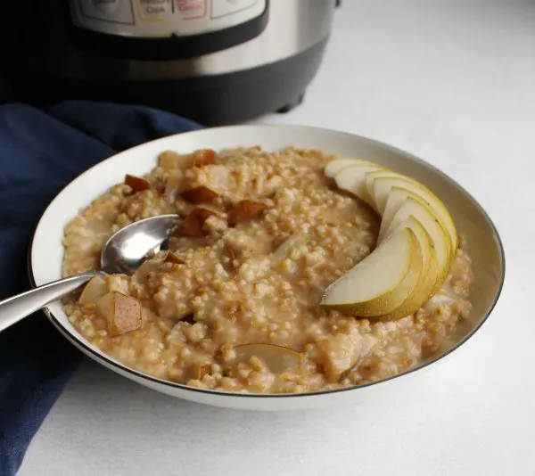Bowl of steel cut oatmeal with honey and pears in front of Instant Pot.