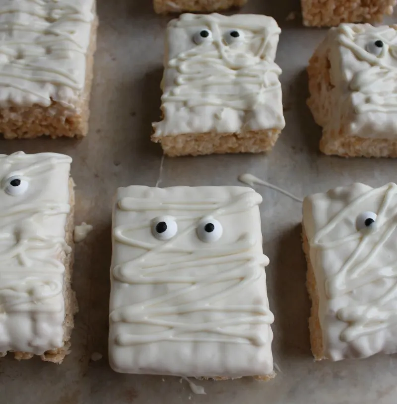 Rice krispie treats decorated with white chocolate and candy eyeballs to look like mummies.