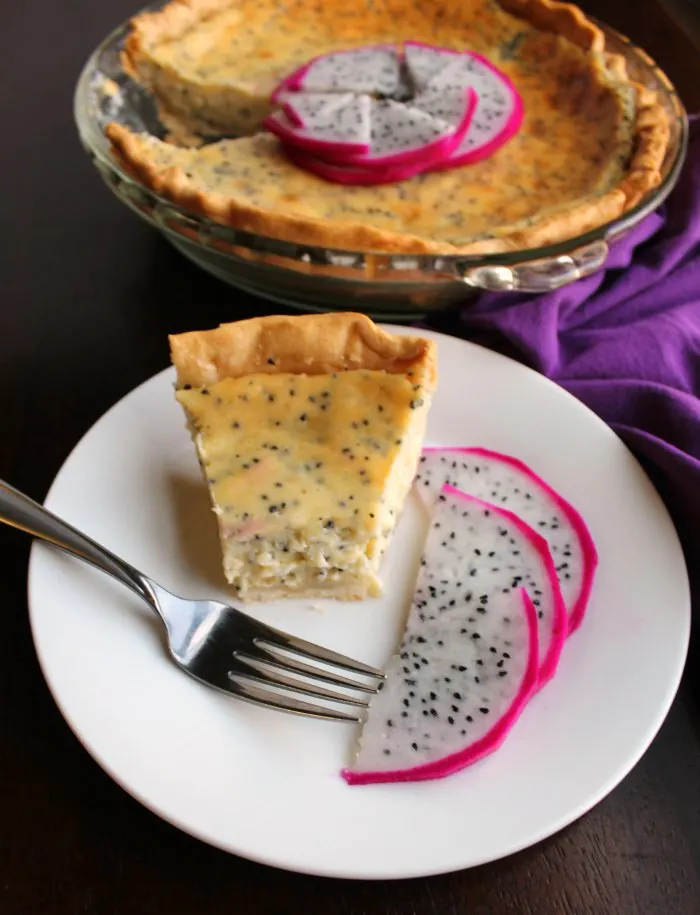 Piece of dragonfruit pie with a bite missing on plate next to sliced dragonfruit.