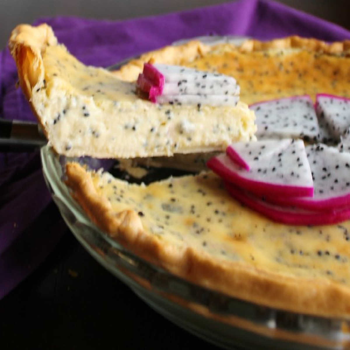 first slice of dragon fruit pie being lifted out of pie plate with creamy center dotted with black seeds showing.