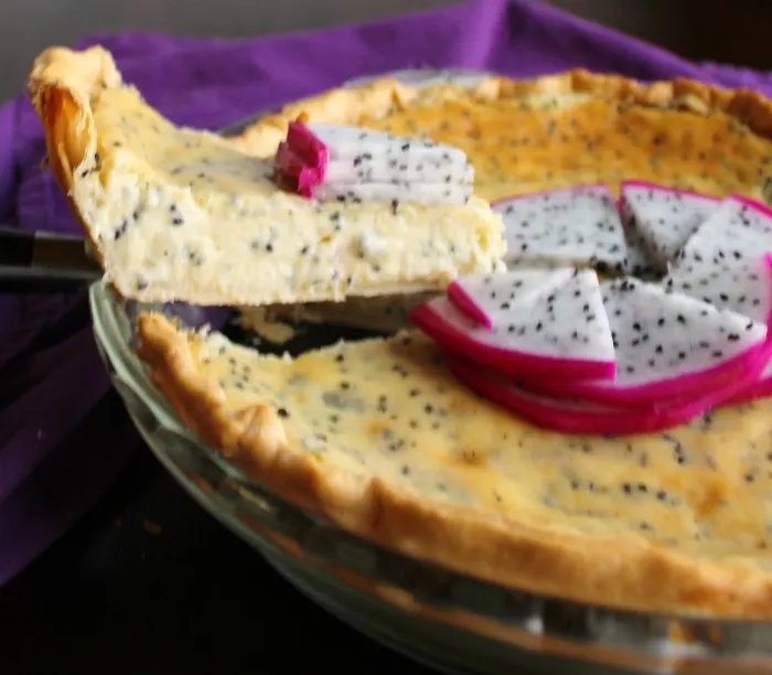 first slice of dragon fruit pie being lifted out of pie plate with creamy center dotted with black seeds showing.