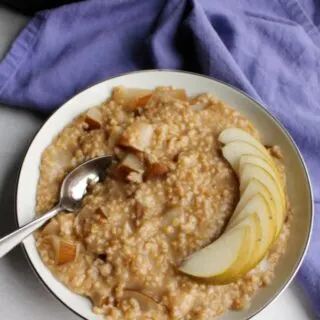 bowl of steel cut oatmeal with slices of fresh pear on top with instant pot in background.