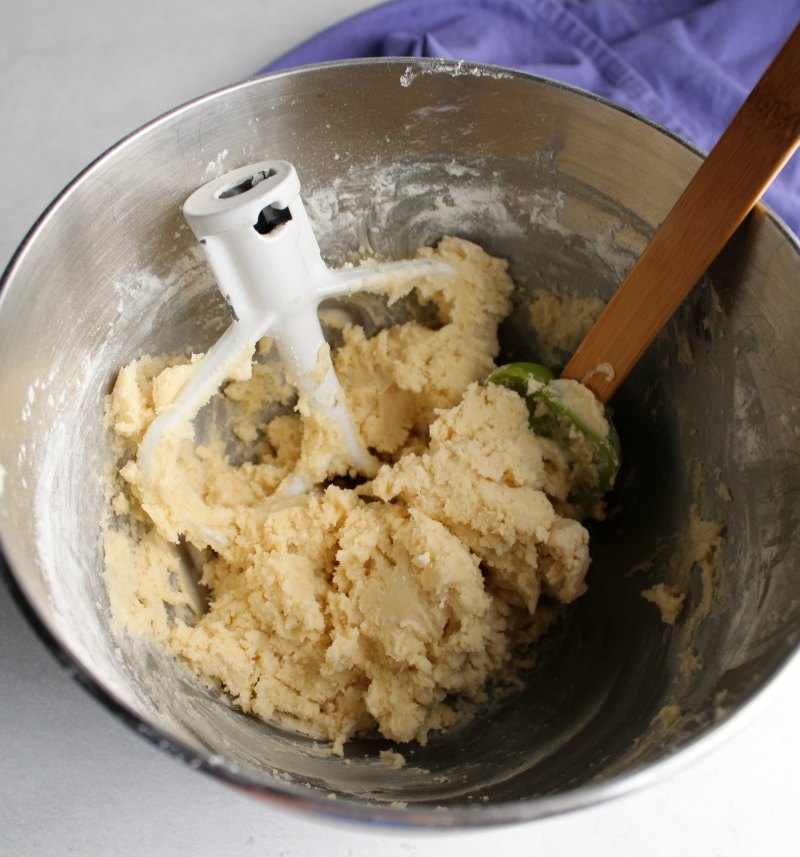 mixer bowl full of melting moments cookie dough with paddle and spatula.