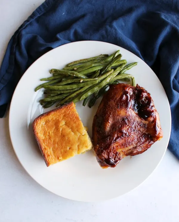 dinner plate with bbq chicken, corn casserole and roasted green beans.