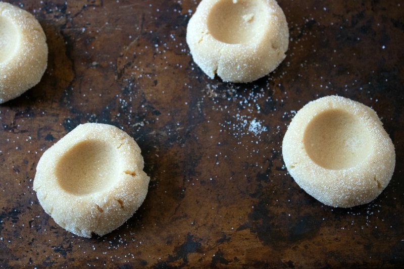 Balls of peanut butter cookie dough coated in sugar with circular indents in the center.