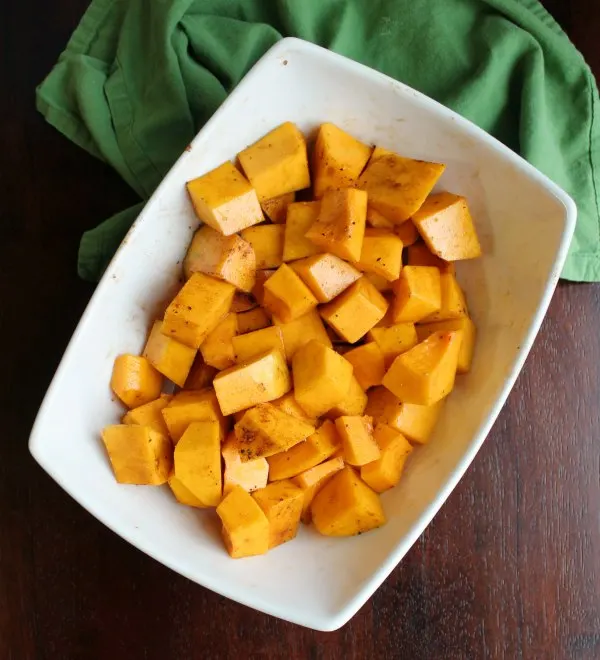 cubes of butternut squash tossed in oil and seasoning and ready to go into the air fryer.