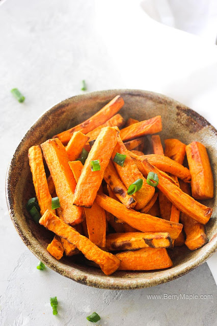 Bowl of sweet potato fries topped with parsley.