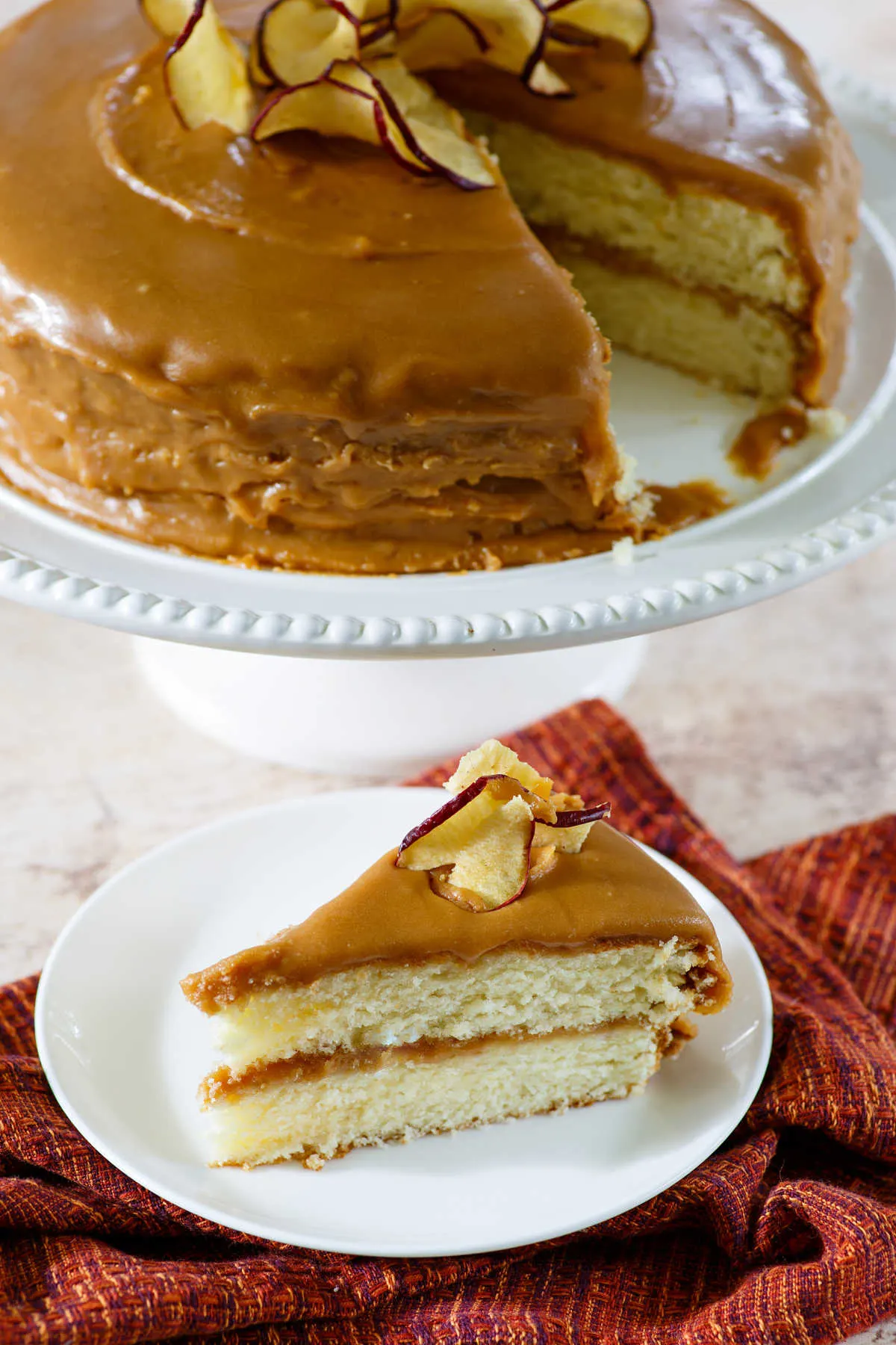 homemade southern caramel cake with caramel icing and apple chips one slice served.