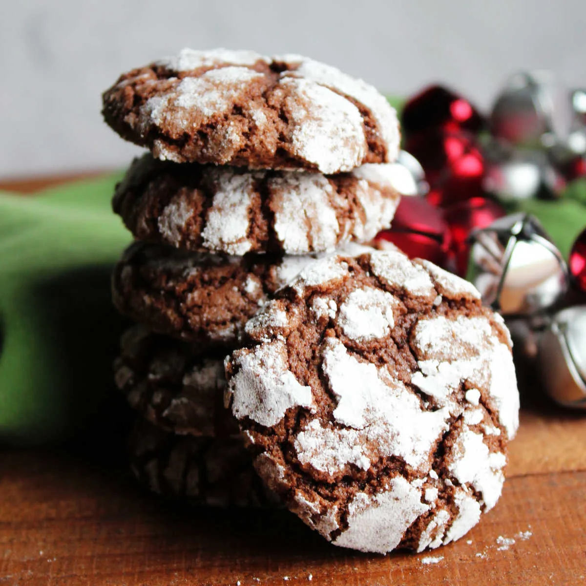 Stack of chocolate crinkles cookies with bits of the chocolate interior showing through the crackled powdered sugar exterior.