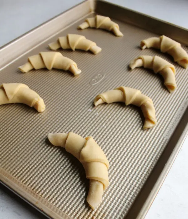 crescent roll dough rolled into horns and ready to proof.